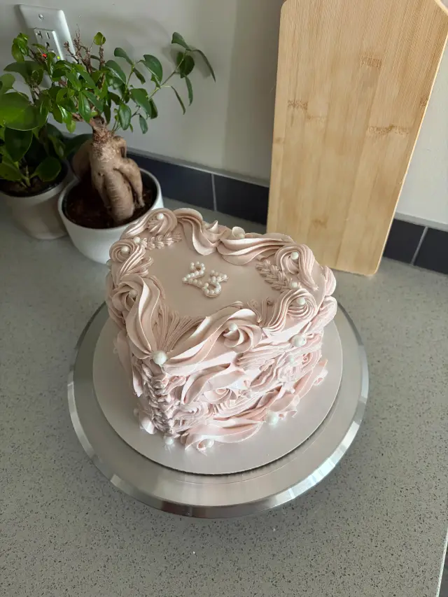 Blush pink cake covered in vintage-style piped scrollwork across the top and down the sides.
