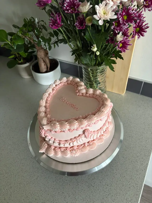 Pale pink heart-shaped cake with layers of vintage piped ruffles and shells, and Seventeen written in pink script on top.
